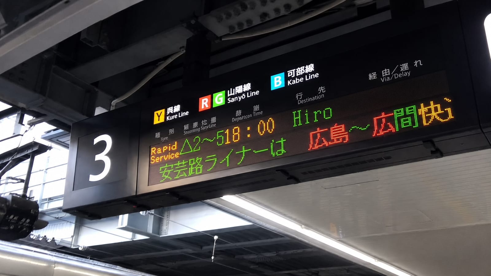 The departure board above platform 3 at Hiroshima Station: the yellow Y marks Kure Line services, with a scrolling notice about the Akiji Liner rapid.
