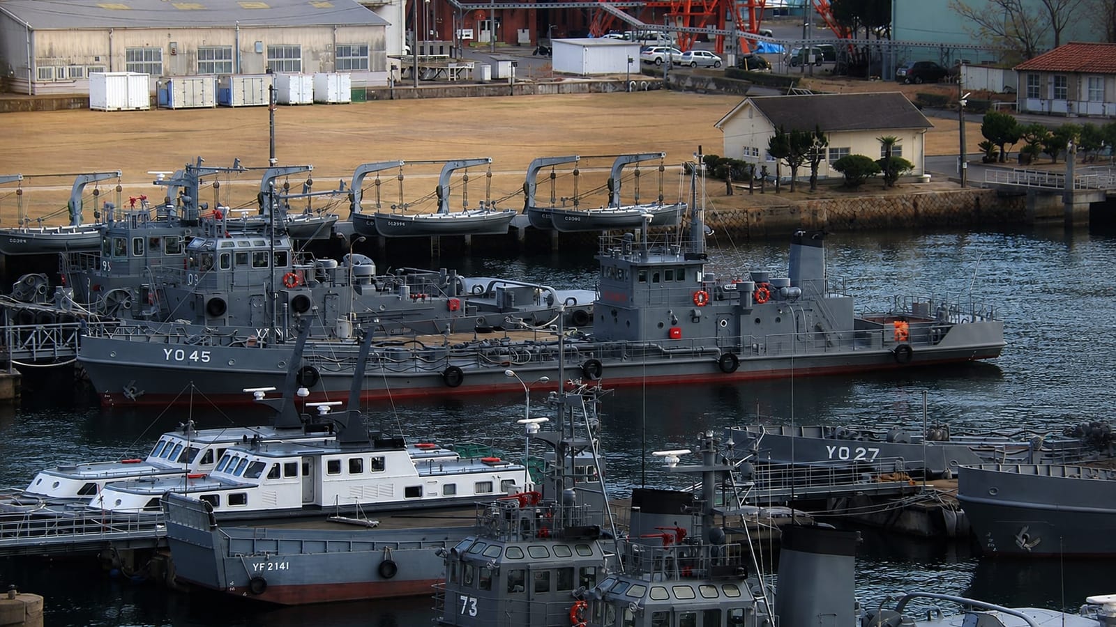 Yard boats and harbour support craft clustered at the base's small-craft piers, seen from inside the base during an open-ship day.