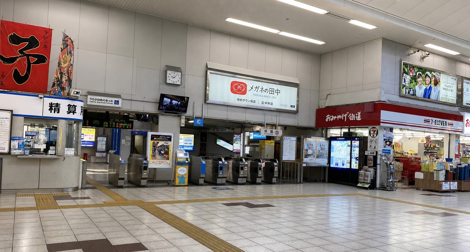 The ticket gates at JR Kure Station, with a 7-Eleven and the Omiyage Kaido souvenir shop on the right. Exit here and turn toward the harbour side.