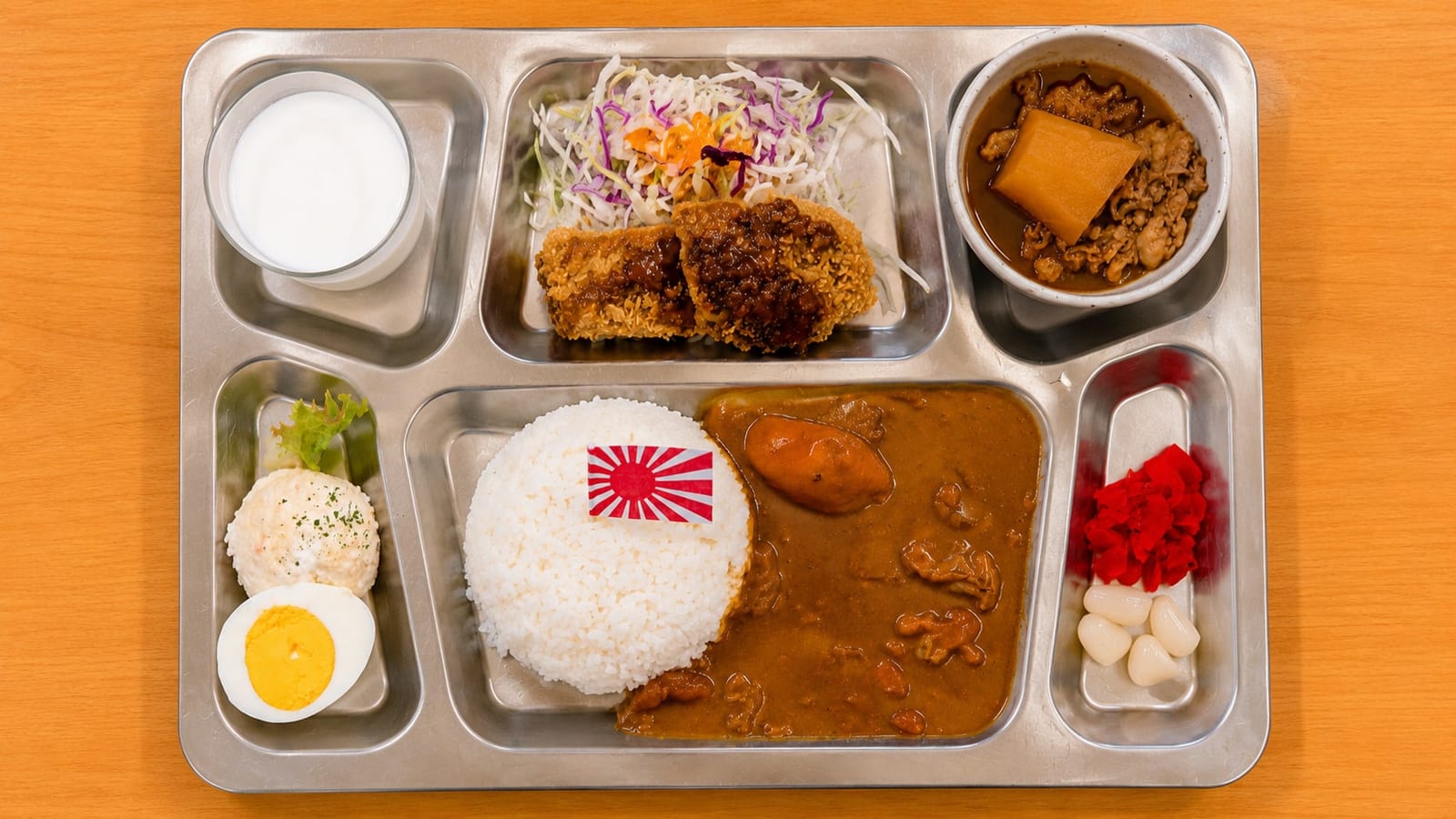 The Sōryū Teppan Curry at Kure Haikara Shokudou, one to two minutes from the museum, seen from above on a JMSDF-style stainless mess tray: curry and rice, a fried cutlet, nikujaga stew, potato salad, pickles, and the standard glass of milk.